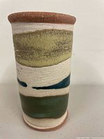 Front view of cylindrical stoneware goblet showing cream body and green bands