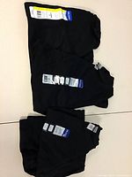 Stacked black Gildan T-shirts folded with tags visible