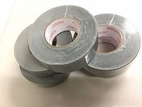 Five grey duct tape rolls stacked, labels visible