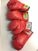 Four red Everlast boxing gloves (two pairs) laid out showing logos