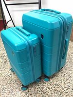 Two turquoise Heys hard-shell spinner suitcases, one smaller carry-on and one medium size