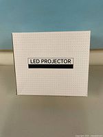 Front of unopened white box labeled LED PROJECTOR