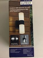 Front of retail box showing Lutec outdoor LED cylinder sconce with mount options