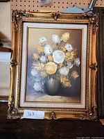 Front view of framed floral oil painting in ornate gold frame showing signature