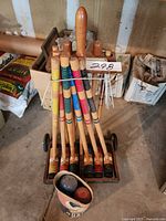 Full view of croquet set with mallets, balls in tube, stakes and wickets on rolling stand