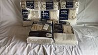 Five unopened packs of Eclipse Duotech blackout curtain pairs on bed