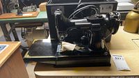 Left side view of Singer Featherweight sewing machine on base with extension bed open
