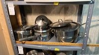 Shelf with stockpot, stack of steamer/double-boiler inserts, saucepan and lids