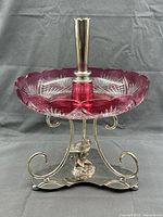 Front view of silver-plated stand with bird figure and cranberry cut glass bowl and trumpet