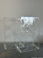 Front view of both clear Lucite wine bottle racks showing circular cutouts