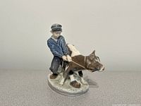 Front left view of porcelain figurine showing boy and calf detail