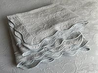 Folded pillow shams atop bedspread showing matelassé pattern and scalloped edges