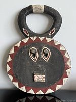 Front view of carved wooden Goli Kple Kple mask showing paint, eyes, mouth, triangular border, handle