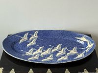Top view of oval blue speckled platter with cream flying cranes
