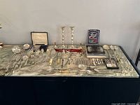 Full lot overview on countertop showing candelabra, large assortment of silver plated utensils and accessories