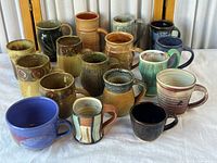 Group shot of all 18 handmade ceramic mugs from front angle