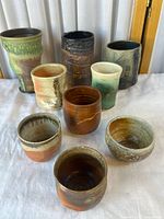 Nine assorted ceramic cups front and back rows