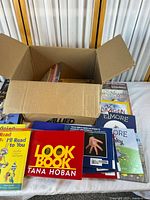 Open box with assorted books spread on table