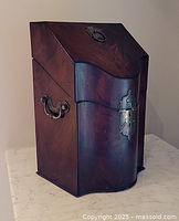 front view of wooden cutlery box showing brass escutcheon and curved front