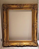 Full view of large gilt wood frame leaning against wall
