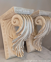 Front angled view of both plaster corbels showing scroll design
