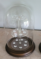 glass dome over tiered thimble stand on wooden base