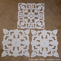 Three white carved wood panels displayed on floor