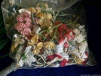 Assorted small fabric and ribbon flowers inside clear bag