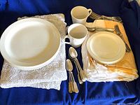 Overall lot with plates, mugs, cutlery and folded tablecloths