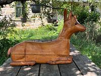 Front view of carved wood deer lying on table outdoors