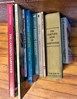 Seven gardening and homesteading books standing upright on shelf