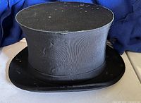 Black satin top hat front and side view showing fabric damage