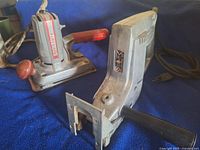 Reciprocating saw foreground, sander background on blue cloth