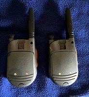 Rear view of both Cobra radios showing battery doors and antennas
