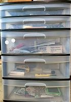 Full view of five-drawer plastic dresser showing contents through translucent drawers