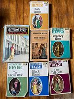 Front covers of seven Georgette Heyer novels laid out on wood floor