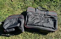 Both Samsonite black soft luggage pieces lying on grass