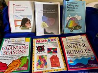Top row spiral-bound Red Flags, Checkered Flags, Aboriginal History; bottom Little Scholars titles and MathART