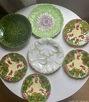 Seven majolica plates on table showing variety