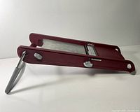 Side view of burgundy DeBuyer mandoline showing support leg and deck