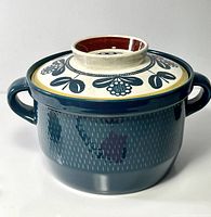 Front view of covered casserole showing teal body and patterned lid