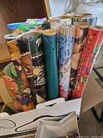 Group of approx. 13 wrapping-paper rolls standing upright showing various patterns