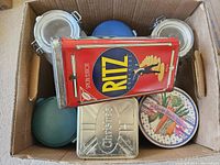 Boxed grouping shows Ritz tin, silver Christie tin, round vegetable tin, two glass jars, blue/teal lids visible