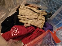 Bag containing assorted leather gloves, knit gloves and red Olympic mittens
