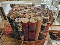 Vertical view of numerous Christmas wrapping paper rolls in box
