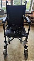 Front view of black Drive Medical lightweight transport wheelchair with footrests on seat and plastic on wheels