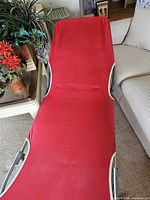 Chair fully unfolded, view of red sling surface and white piping