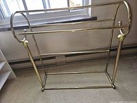 Full view of brass quilt rack showing three rails and freestanding frame