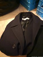 Black wool-blend coat folded showing button and collar