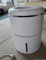 Full view of cylindrical dehumidifier with power cord attached